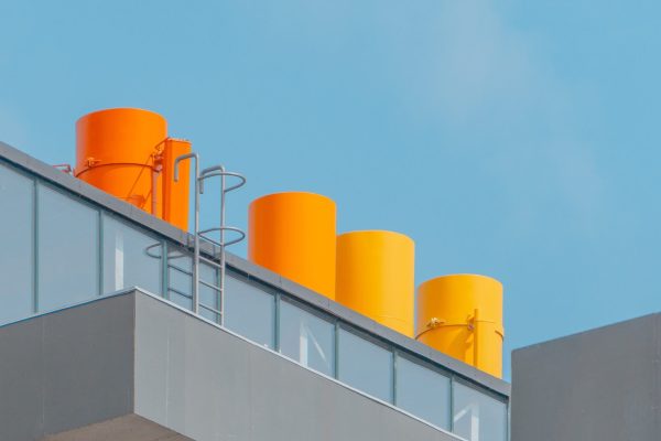 vertical-shot-glass-building-with-orange-chimneys-blue-sky